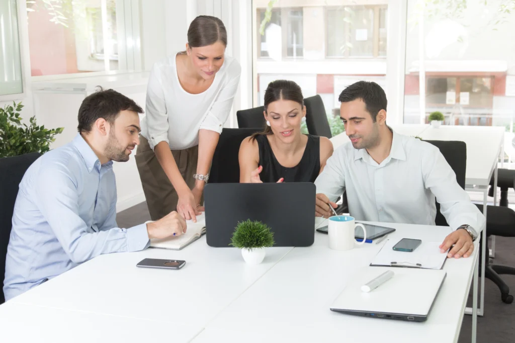 Group collaborating around a laptop in office.