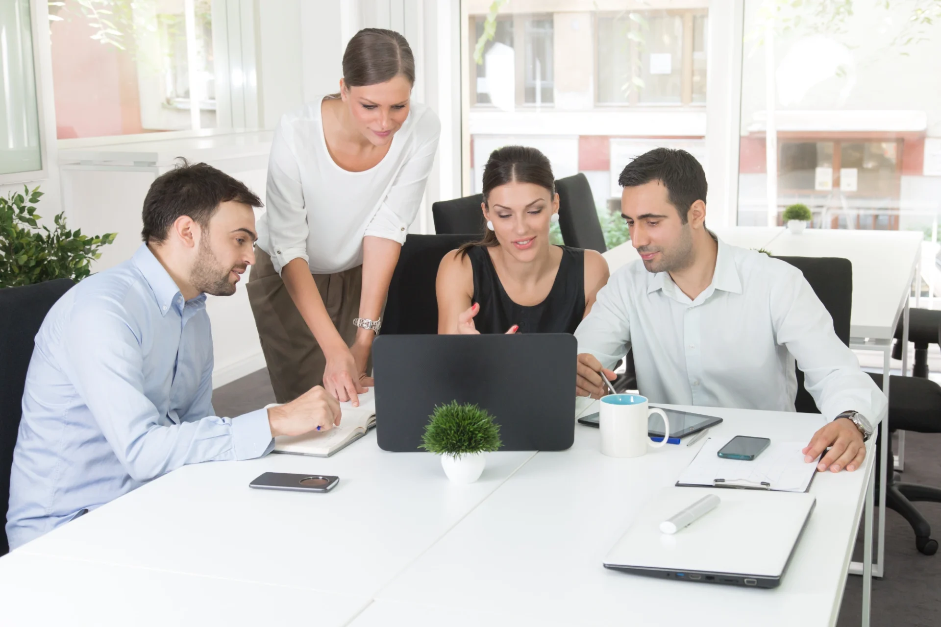 Group collaborating around a laptop in office.